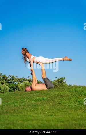 Mature couple doing yoga on lawn in sunshine together Stock Photo