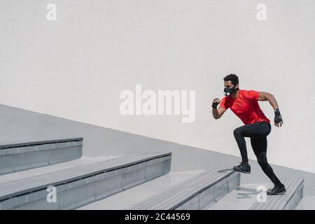 Sportsman wearing face mask running up stairs Stock Photo