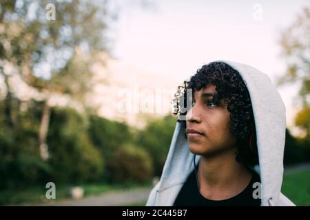 Thoughtful boy wearing hooded jacket looking away in park Stock Photo