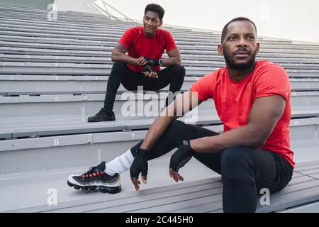 Two sportsmen sitting on stairs in a stadium Stock Photo