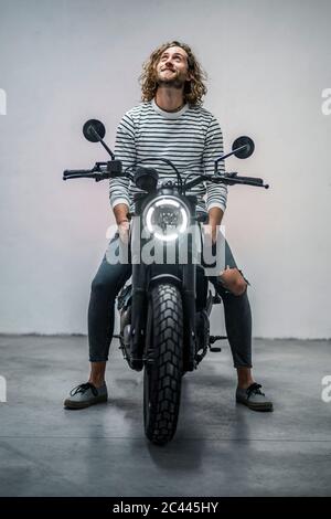 Young man looking up sitting on motorcycle Stock Photo