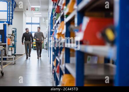 Two men walking and talking in factory Stock Photo