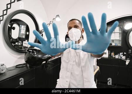 Barber wearing surgical mask and reusable gloves Stock Photo