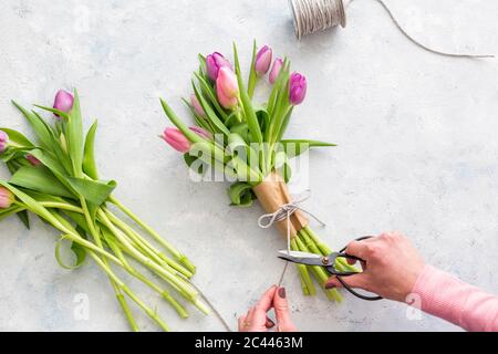 Hands of woman preparing bouquet of purple blooming tulips Stock Photo