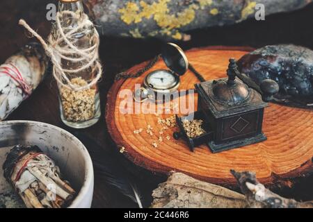 Close up of mess in a witch's kitchen. Wiccan with altar filled with sage smudge sticks, dried herbs, bottles, crystals, tree barks. Messy work space Stock Photo