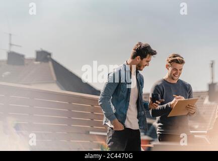 Colleagues brainstorming on balcony, writing down their ideas Stock Photo