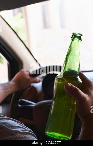 An unrecognizable man drinking beer while driving car. Concepts of ...