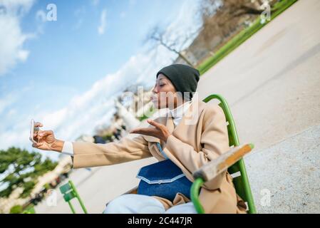 Young woman puckering while taking selfie through smart phone at roadside in Paris, France Stock Photo