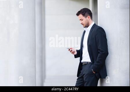 Businessman wearing suit looking on smartphone Stock Photo