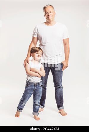 Portrait of father and his little son standing in front of white background Stock Photo