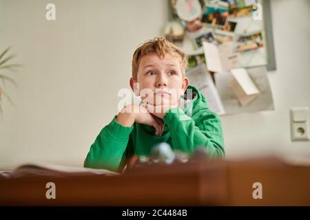 Thoughtful boy looking away while studying at home Stock Photo