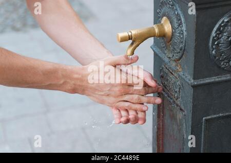 Man washing his hands at fountain, Sardinia, Italy Stock Photo