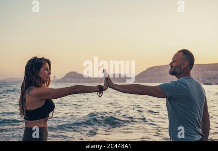 Mature couple touching hands at beach during sunset Stock Photo