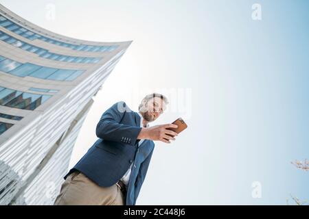 Smiling businessman using smartphone in the city Stock Photo
