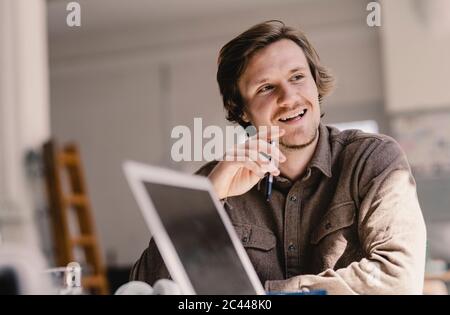 Young man sitting at table, thinking about business ideas Stock Photo