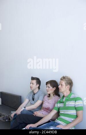 Three friends are sitting in a row Stock Photo - Alamy