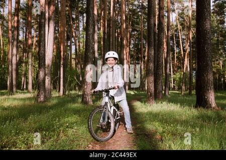 Happy boy with bicycle in forest Stock Photo