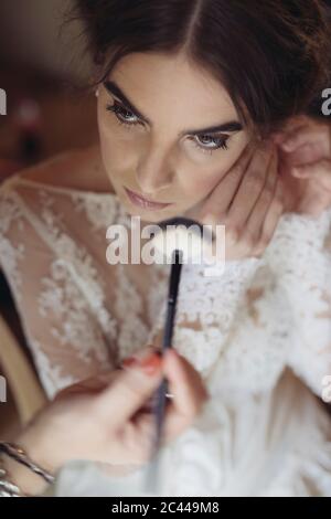 Hands applying cosmetics on face of bride Stock Photo