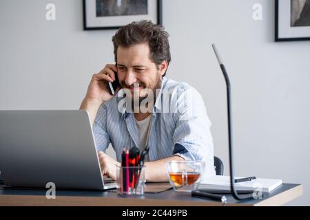 Man using laptop and calling at home Stock Photo