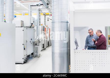 Two businessmen having a discussion in a factory Stock Photo