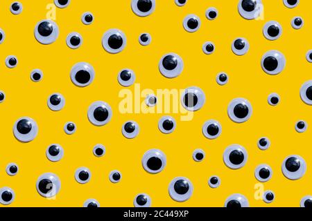 Studio shot of large number of googly eyes against yellow background Stock Photo
