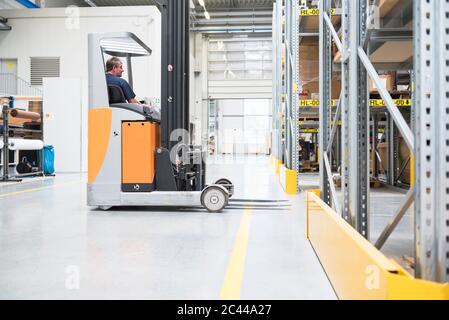 Worker on forklift in high rack warehouse Stock Photo