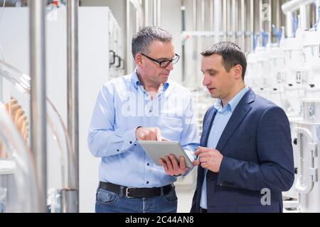 Two businessmen with tablet having a discussion in a factory Stock Photo