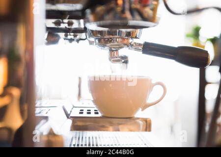 Coffee being poured in cup from espresso maker in shop Stock Photo