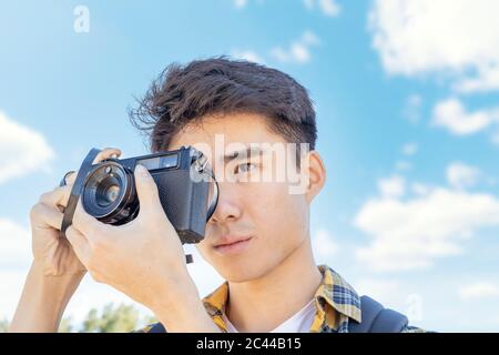 Portrait of young man taking photos with camera Stock Photo