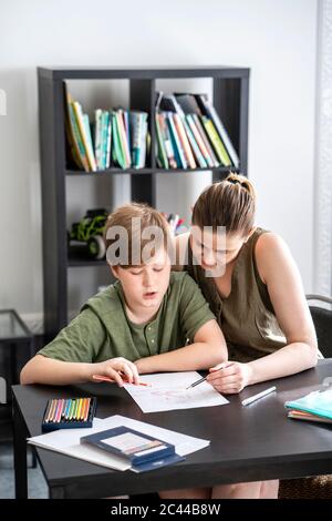 Mother and son looking down at homework at dining room table Stock ...