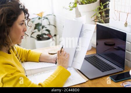 Woman working at desk in home office reviewing documents Stock Photo