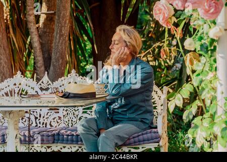 Portrait of senior woman with eyes closed relaxing on garden bench Stock Photo