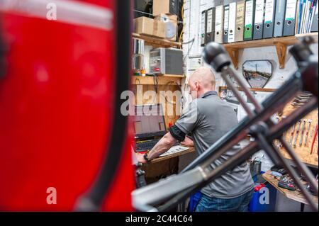 Bicycle mechanic working in bike shop using computer Stock Photo