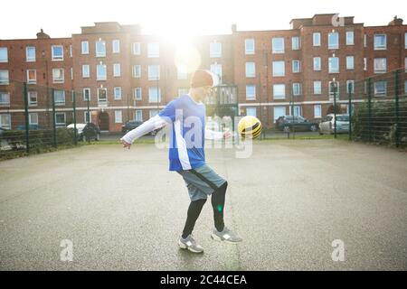 Mature man playing with football on football ground in the city Stock Photo