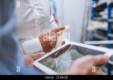 Close-up of two businessmen with tablet and product in a factory Stock Photo