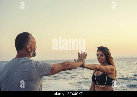 Mature couple touching hands at beach during sunset Stock Photo