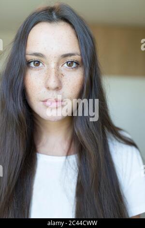 Close-up portrait of beautiful young woman with long brown hair at home