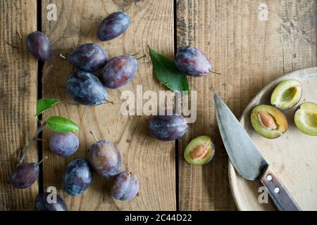 Kitchen knife and fresh plums on wooden surface Stock Photo
