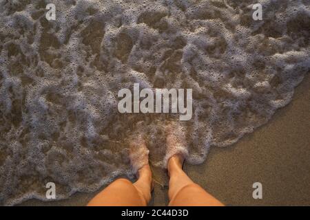 Feet of woman standing at seafront Stock Photo