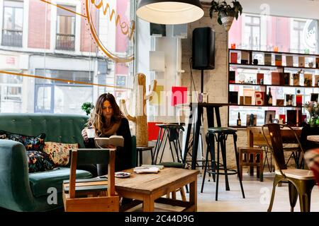 Woman drinking coffee and reading book in coffee shop Stock Photo