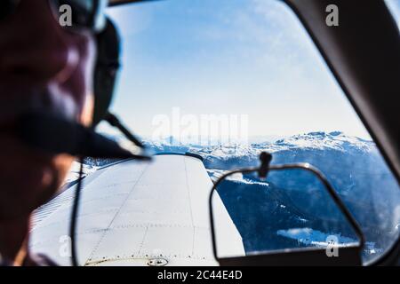 Austria, Tyrol, Steinberg am Rofan, Pilot looking through window during flight over mountain range Stock Photo