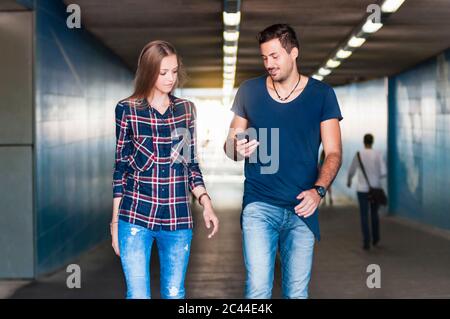 Young man and young woman walking together in an underpass Stock Photo