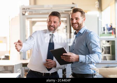 Two smiling businessmen with tablet having a meeting in a factory Stock Photo