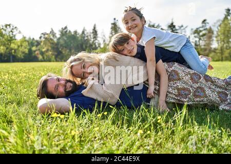 Happy family lying on grass during sunny day Stock Photo