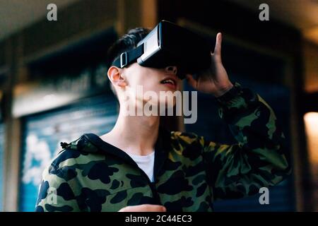 Young man looking through virtual reality simulator outdoors Stock Photo