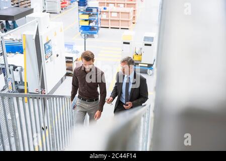 Two businessmen walking up stairs in a factory Stock Photo