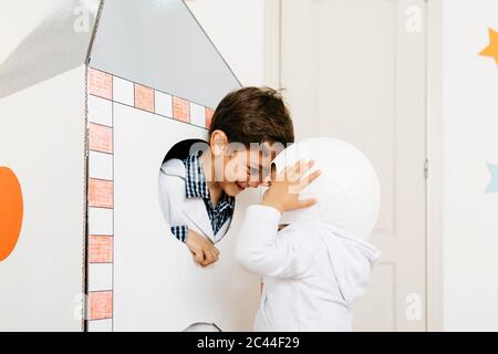 Siblings playing astronaut and researcher at rocket Stock Photo