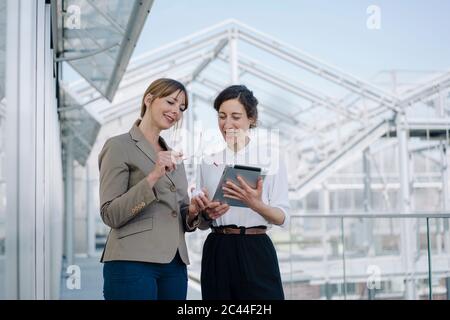 Two businesswomen with tablet and wind turbine model having a meeting at a greenhouse Stock Photo