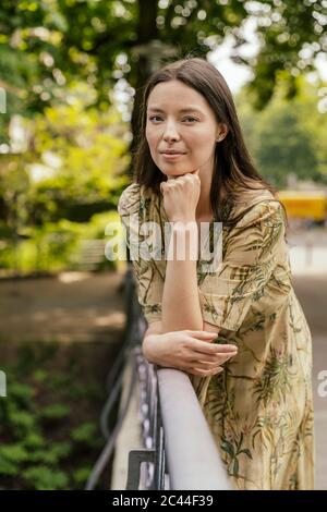 Portrait of woman leaning on bridge railing Stock Photo