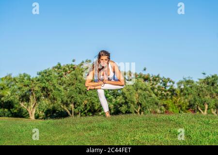 Portrait of woman doing yoga on lawn in sunshine Stock Photo